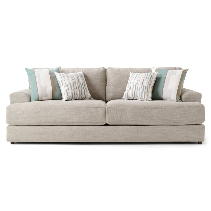 A light beige or taupe colored sofa is centered against a white background.    The sofa is a standard, two-seat style with a low-profile design.    The upholstery appears to be a textured fabric.   The sofa is adorned with a set of decorative throw pillows in muted shades of teal, beige, and white, featuring patterned designs. The pillows are layered and nestled on the sofa's back cushions.   The sofa's legs are a darker shade of taupe or black and are minimal in style.